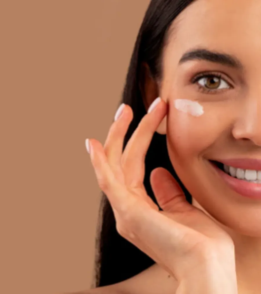Smiling woman applying cream to her cheek